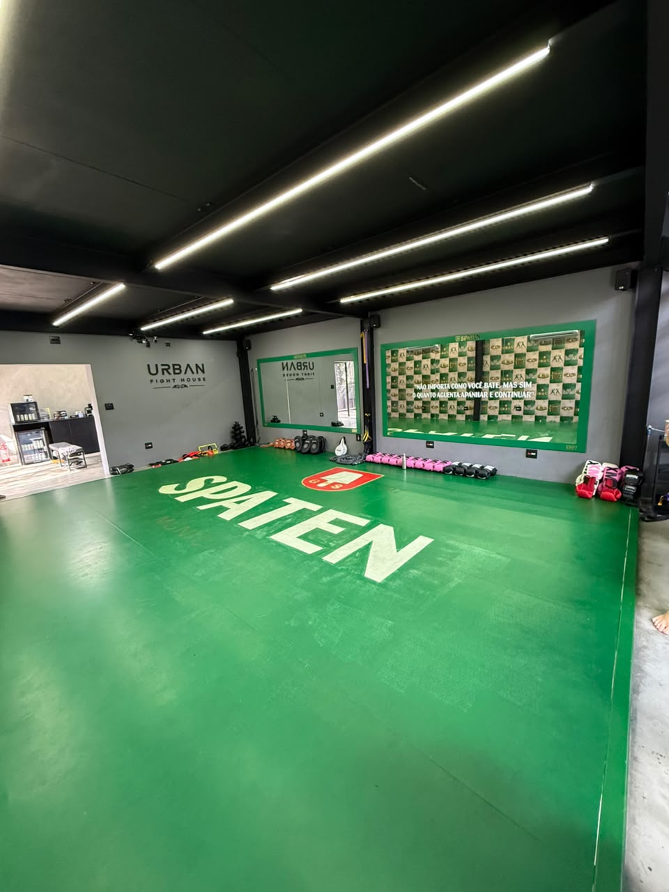 Tatame verde com logo Urban Fight House na parede da unidade Vila Olímpia