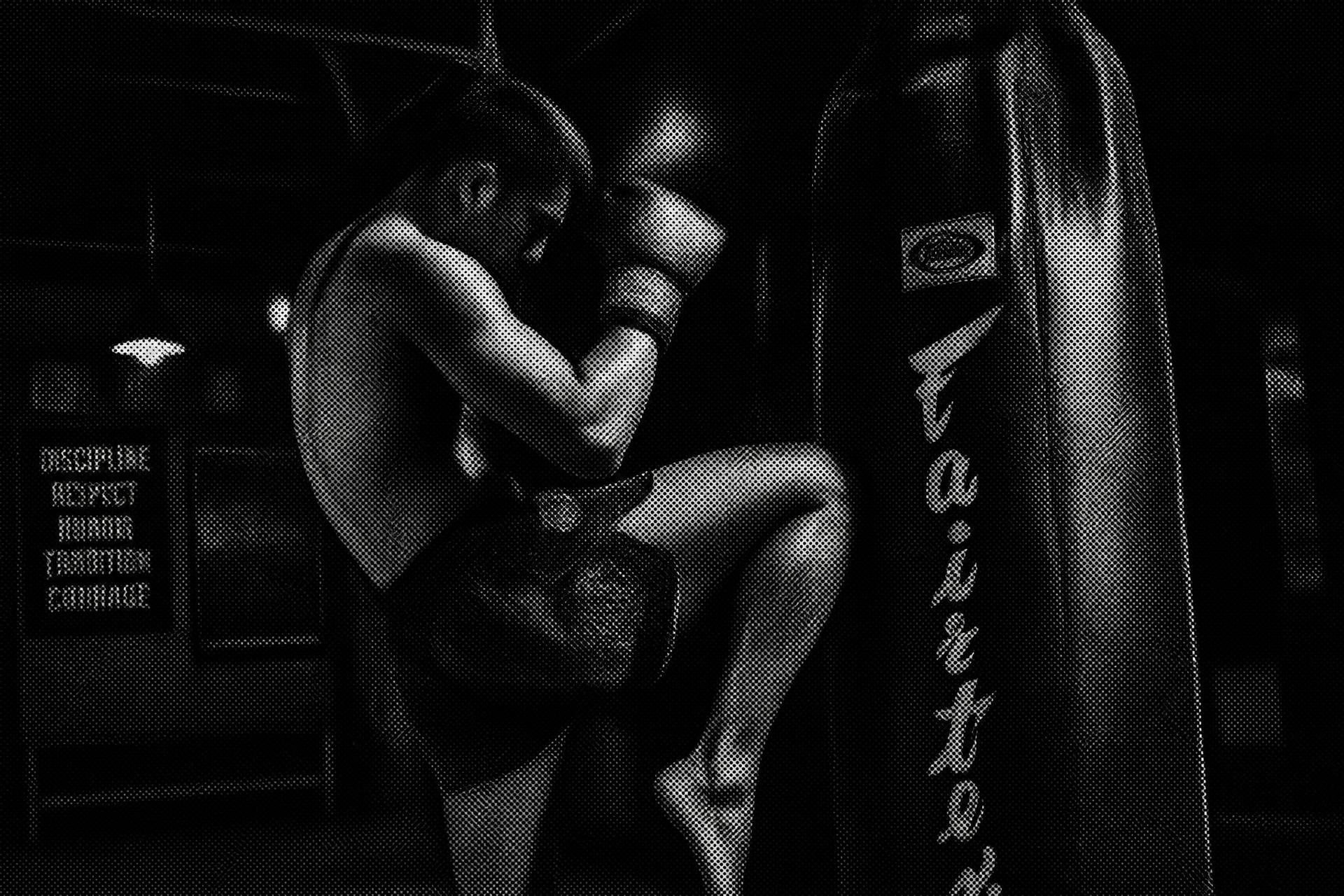 Atleta de luvas aplicando joelhada no saco de pancadas durante treino de muay thai